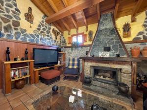 a living room with a stone fireplace and a tv at Casa Obis in Muñeca