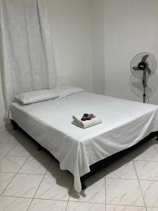 a bed with a white sheet and a book on it at BARU ESTELAR in Medellín