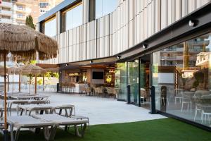 an outdoor patio with tables and chairs and umbrellas at Hotel Primavera Park in Benidorm