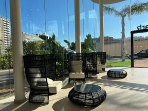 a group of chairs and tables in a building with windows at Hotel Primavera Park in Benidorm