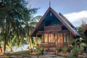 a house on the beach with palm trees at Bayu Lestari Island Resort in Mersing