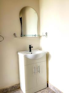 y baño con lavabo blanco y espejo. en majestic cottage, en Ayaso