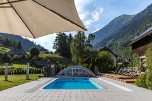a swimming pool with an umbrella and mountains in the background at Ferienwohnung Aigner im Salzburger Lungau in Muhr