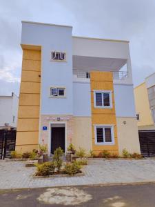 a white and yellow building with plants in front of it at Highly Secured 24 Hours Electricity Apartment in Garki