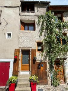 une maison avec une porte rouge et un garage rouge dans l'établissement Petite maison de vacances en Cévennes, à Florac Trois Riviere