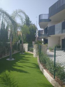 ロ・パガンにあるModern nieuwbouwappartement aan het strand van de Mar Menor in Santiago de la Riberaのヤシの木が茂る建物前の芝生