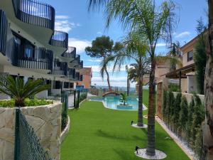 a resort yard with a pool and palm trees at Modern nieuwbouwappartement aan het strand van de Mar Menor in Santiago de la Ribera in Lo Pagán