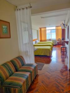 Habitación de hotel con 2 camas y sofá en Hostal Solari, en Trujillo