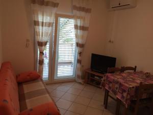 a living room with a couch and a table and a television at Apartments by the sea Stara Novalja, Pag - 234 in Stara Novalja
