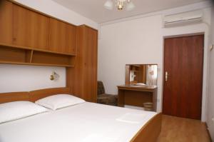 a bedroom with a white bed and wooden cabinets at Apartments by the sea Simuni, Pag - 236 in Kolan