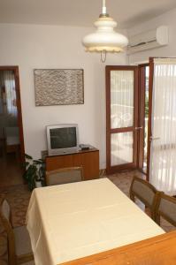 a dining room with a table and a television at Apartments by the sea Simuni, Pag - 236 in Kolan
