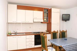 eine Küche mit weißen Schränken, einem Tisch und einem TV in der Unterkunft Apartments by the sea Kneza, Korcula - 167 in Račišće