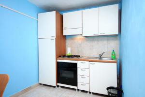 a kitchen with white cabinets and a sink and a refrigerator at Apartments by the sea Brna, Korcula - 171 in Smokvica