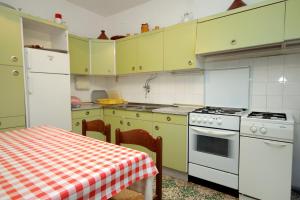 a kitchen with yellow cabinets and a table and a stove at Apartments with parking space Lumbarda, Korcula - 179 in Lumbarda +23 photos