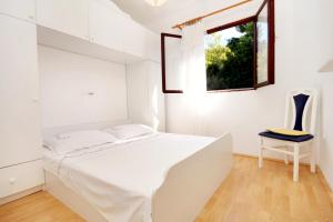 a white bedroom with a bed and a window at Apartment Prizba 219b in Prizba