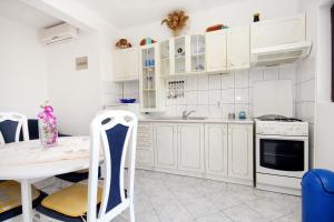 a kitchen with white cabinets and a table and a stove at Apartment Prizba 219b in Prizba