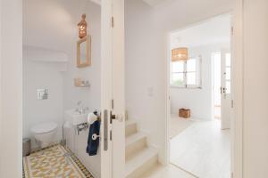 La salle de bains blanche est pourvue de toilettes et d'un lavabo. dans l'établissement Travessa's House, à Olhão