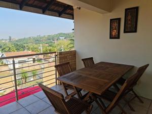 a wooden table and chairs on a balcony at Africatamna Self Catering House in Durban