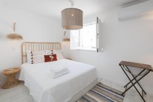 a white bedroom with a white bed and a window at Travessa's House in Olhão
