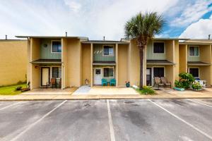 a building with a palm tree in front of a street at Gulf Highlands - 173 Damon Circle in Panama City Beach