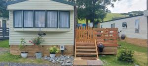 une maison avec une clôture en bois à côté d'un jardin dans l'établissement Westmorland 32 caravan, à Ballantrae