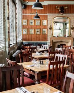 ein Restaurant mit Holztischen, Stühlen und einem Spiegel in der Unterkunft The Bull & Last in London