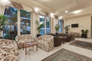 a living room with couches and a tv and windows at Hotel Vela in Milano Marittima