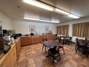 a large kitchen with wooden cabinets and tables and chairs at Americas Best Value Inn and Suites Ada in Ada