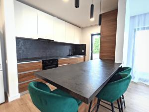 a kitchen with a black table and green chairs at Ira Premium Apartment Cluj in Cluj-Napoca