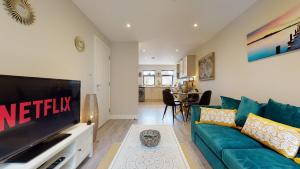 a living room with a green couch and a television at Chatham Serviced Apartments by Hosty Lets in Chatham