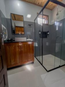 a bathroom with a glass shower and a sink at Pousada Scursel in Ibirama