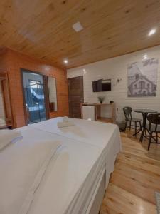 Un dormitorio con una gran cama blanca y una mesa en Pousada Scursel, en Ibirama