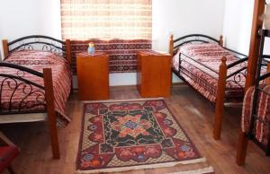 a bedroom with two beds and a rug on the floor at Pottery House Sanahin in Alaverdi