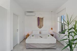 ein weißes Schlafzimmer mit einem Bett und einer Pflanze in der Unterkunft Annassa Suites in Almyrida