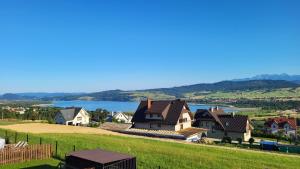 a house on a hill with a lake in the background at Apartament Nad Zaporą in Szlembark