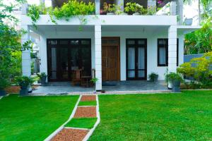 ein Haus mit grünem Rasen davor in der Unterkunft Muthu villa in Ambalangoda
