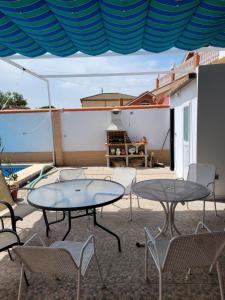 d'une terrasse avec deux tables, des chaises et une table. dans l'établissement Casa cerca de Sevilla con piscina, à Valencina de la Concepción