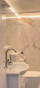 a white bathroom with a sink and a marble wall at Maria Louiza apartment NEAR CENTER in Athens