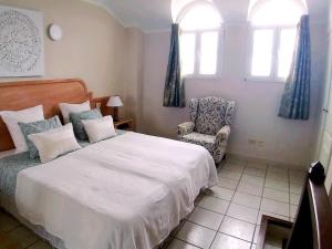 a bedroom with a bed and a chair and windows at For your best holiday in Rocas del Mar with amazing ocean view in Costa Del Silencio