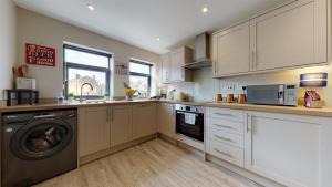 cocina con armarios blancos, lavadora y secadora en Chatham Serviced Apartments by Hosty Lets en Chatham