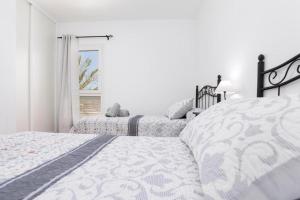 a white bedroom with two beds and a window at Los Majos Fuerteventura in Tarajalejo