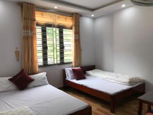 Duas camas num quarto com uma janela em Nhà Nghỉ Minh Hảo em Làng Môn