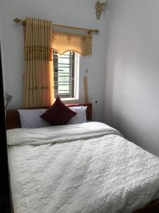 um quarto com uma cama com lençóis brancos e uma janela em Nhà Nghỉ Minh Hảo em Làng Môn