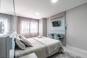 Schlafzimmer mit einem Bett, einem TV und einem Schreibtisch in der Unterkunft 17- Studio Perfeito para casal! in Curitiba