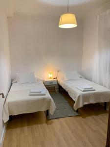 2 camas en una habitación blanca con lámpara en N&E - Home Celanova AVD San Rosendo, en Celanova