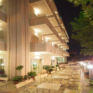 una fila de mesas y sillas fuera de un edificio por la noche en Hotel Muccioli, en Misano Adriatico