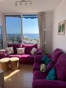 a living room with purple couches and a large window at Precioso apartamento en 5 minutos de la playa in Playa de las Americas
