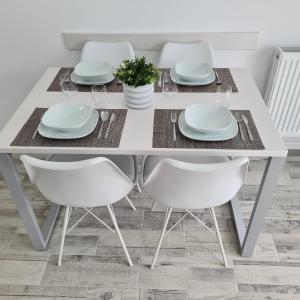 - une table à manger blanche avec des chaises et des assiettes blanches dans l'établissement Panoramic Apartment, à Braşov