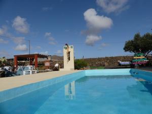 a blue swimming pool with a clock in the middle at Warung in Lajares