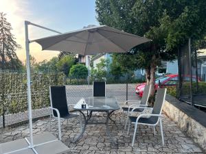 einen Tisch, Stühle und einen Regenschirm auf einer Terrasse in der Unterkunft GOLDSTADT LOUNGE in Pforzheim